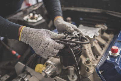 Worker wearing dipped gloves while working in auto shop.