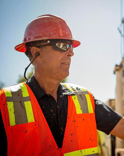 Worker wearing Pyramex Reusable Earplugs, Ridgeline Full Brim, Sealed Eyewear, and Hi-vis Work Wear.